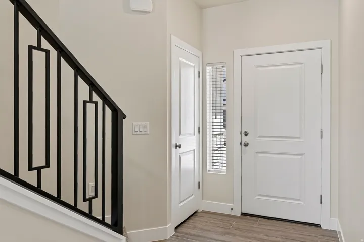 Wood-finish flooring, staircase with geometric black metal balusters, and white panel doors
