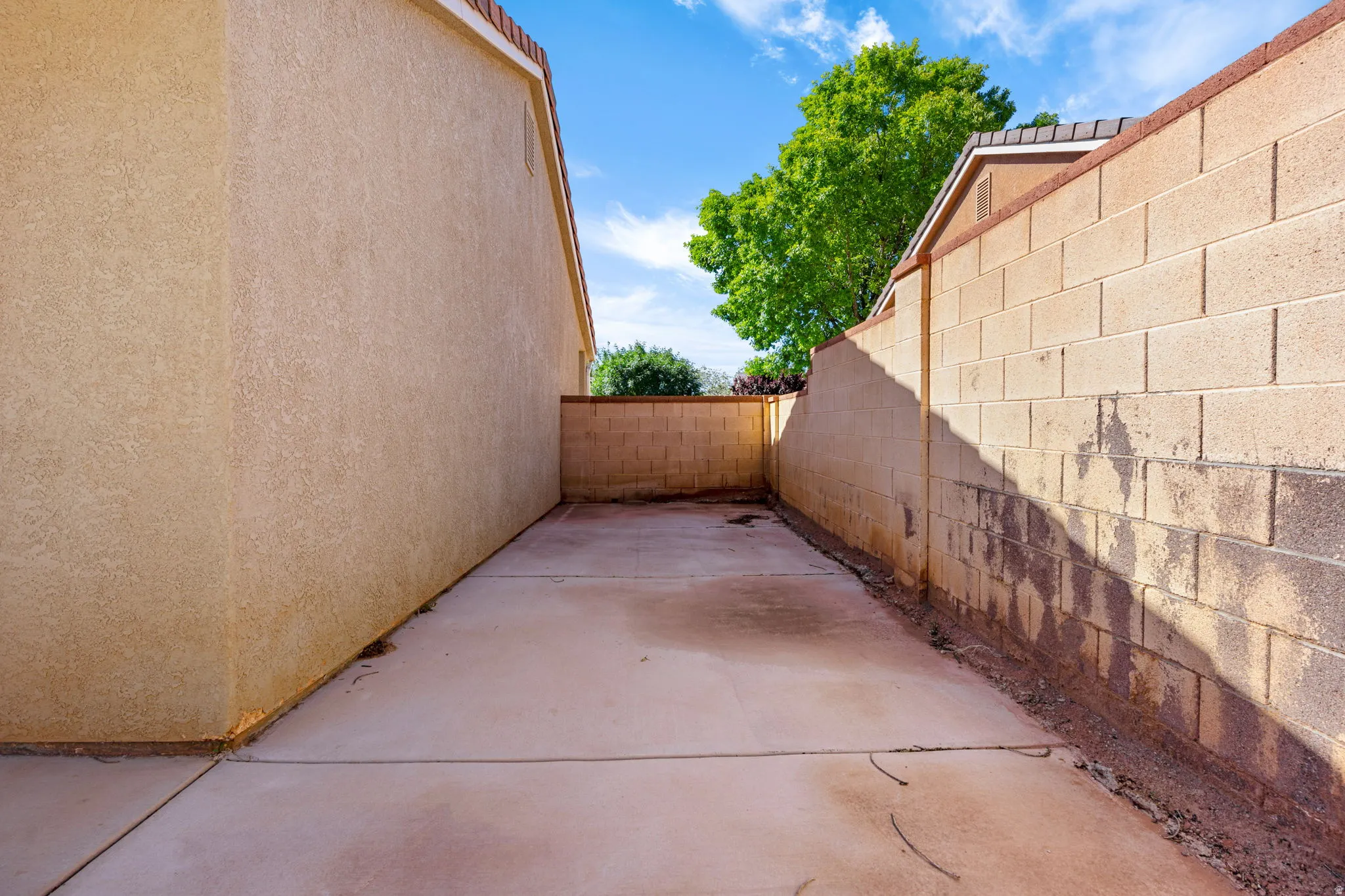 Paved concrete walkway with stucco-finished walls and block privacy fencing