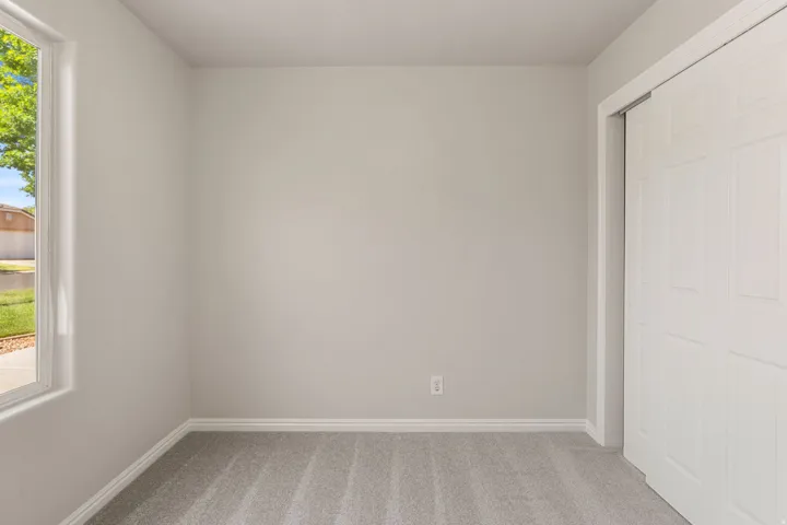 Light-toned carpeted flooring, neutral wall paint, and a white interior door