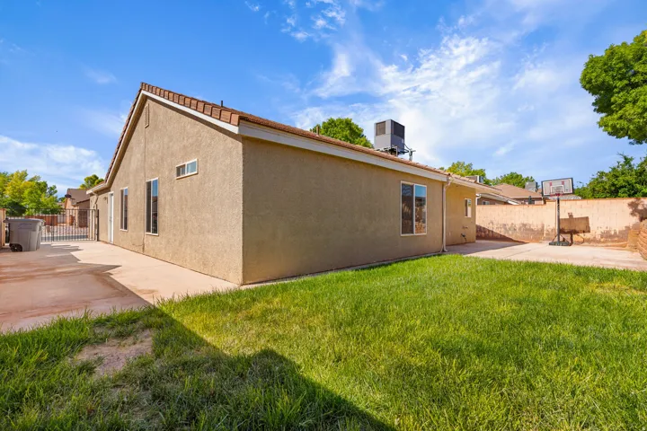 Modern single-story residence with stucco exterior and flat roofline, featuring a spacious rear lawn with mature landscaping and established trees
