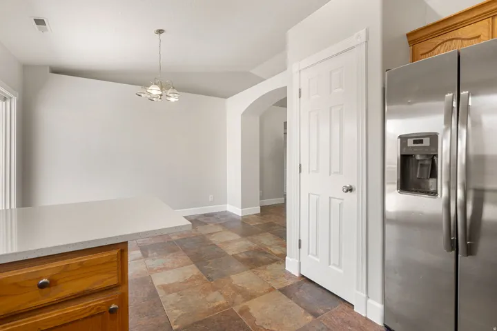 Kitchen island with a light-toned countertop, wood cabinetry, and a stainless steel refrigerator