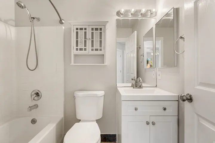 White vanity with integrated sink, brushed nickel faucet, and overhead lighting