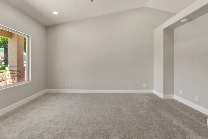 Vaulted ceiling with recessed lighting, light gray carpet flooring, and white trim