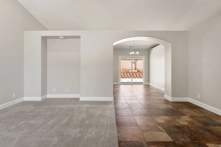 Wall-to-wall carpeting, arched entryway, tile flooring, and sliding glass doors