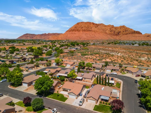 Residential neighborhood with established homes and mature landscaping, set against a backdrop of prominent red rock formations