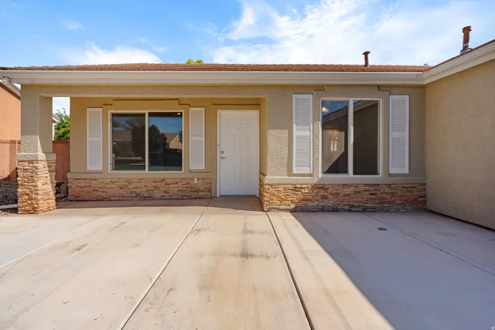 Stucco exterior with stone veneer accents, covered entry, white door, and white window shutters