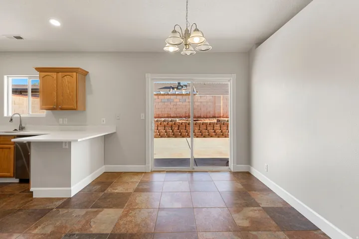 Multitoned tile flooring, sliding glass door, white countertop, wood-finish cabinetry, and stainless steel sink
