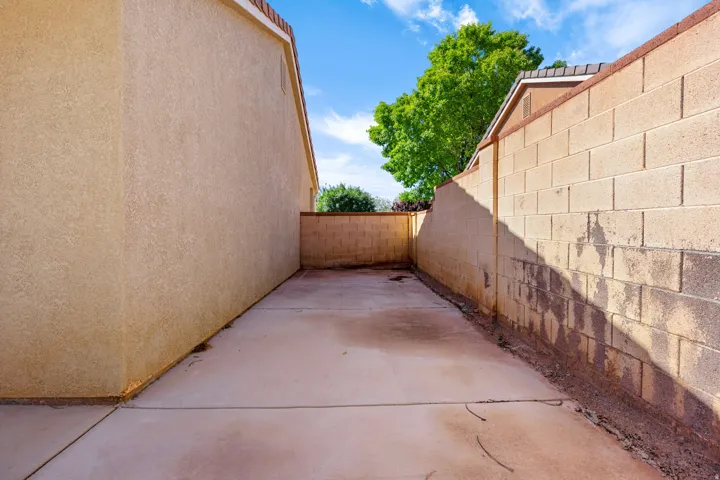 Paved concrete walkway with stucco-finished walls and block privacy fencing
