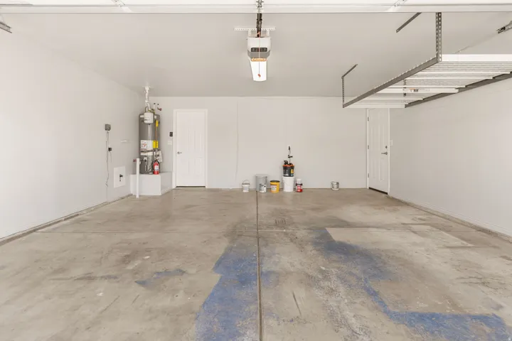 Spacious garage featuring a concrete floor, overhead storage rack, and two entry doors