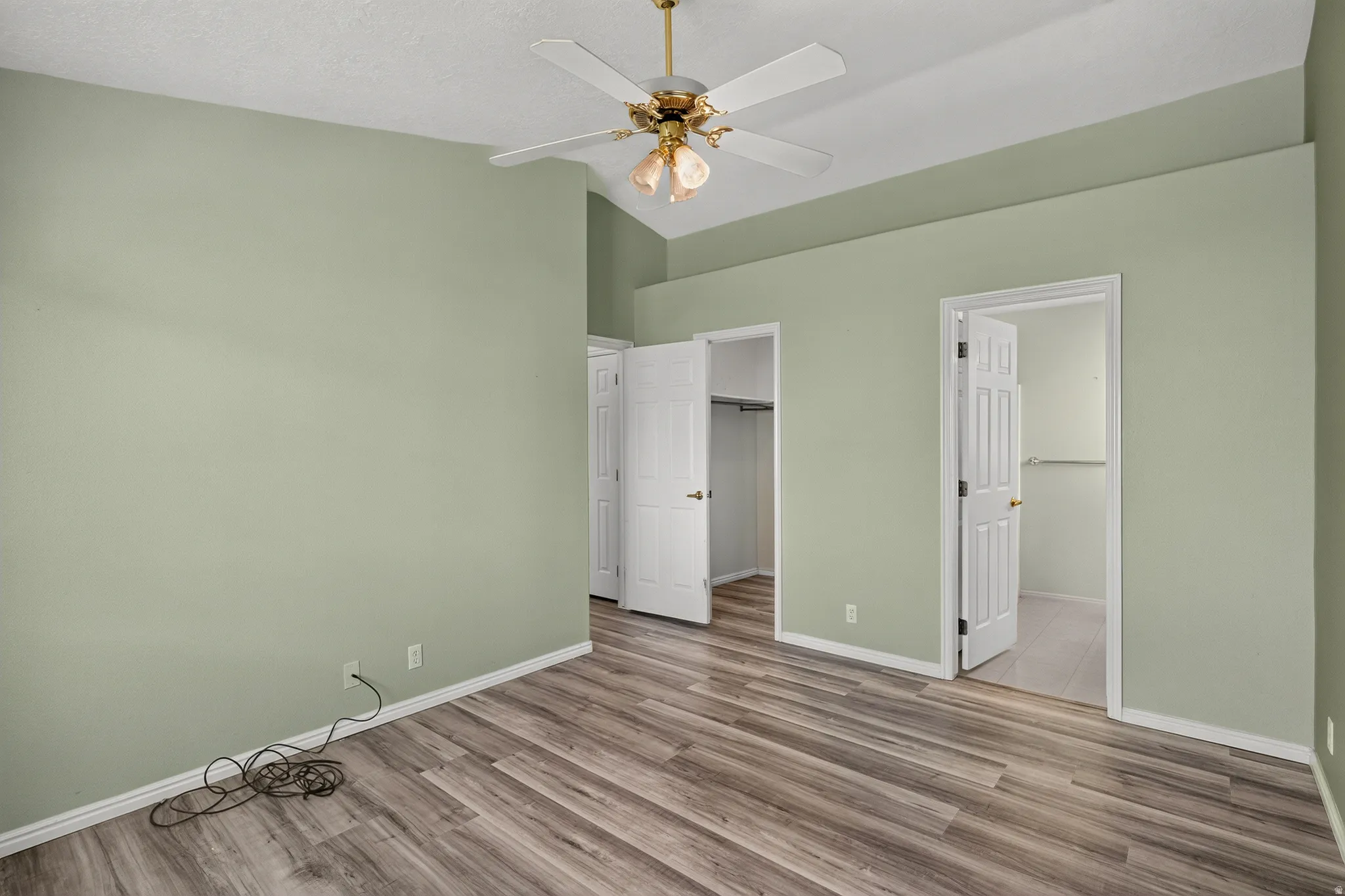 Room featuring wood-finish flooring, vaulted ceiling, and a ceiling fan with integrated lighting