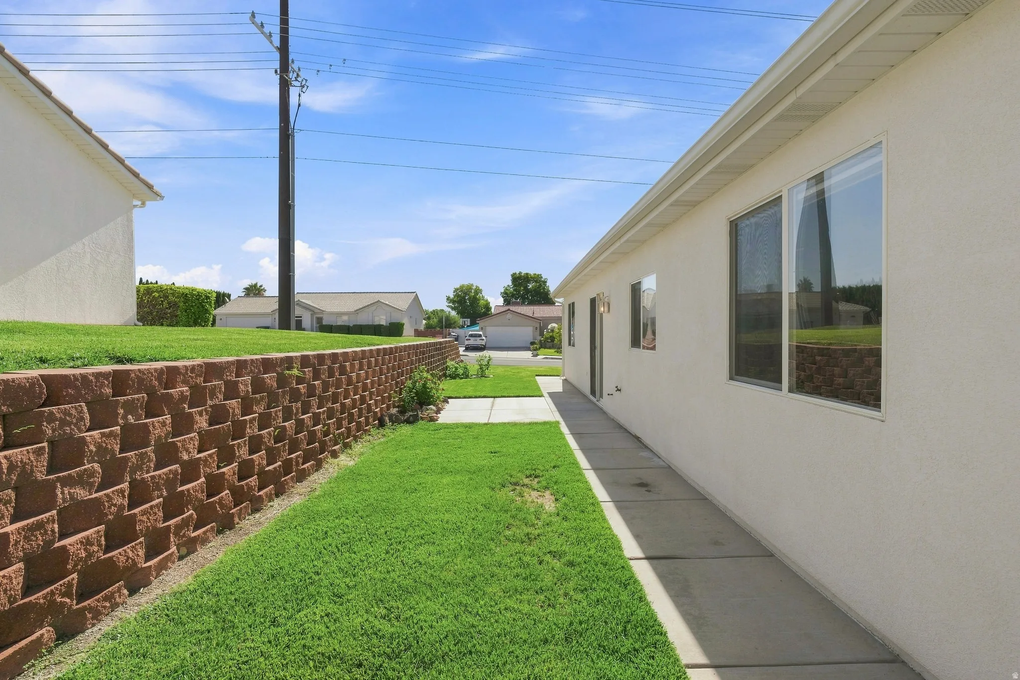 Spacious side yard featuring a lush, manicured lawn bordered by a substantial brick retaining wall