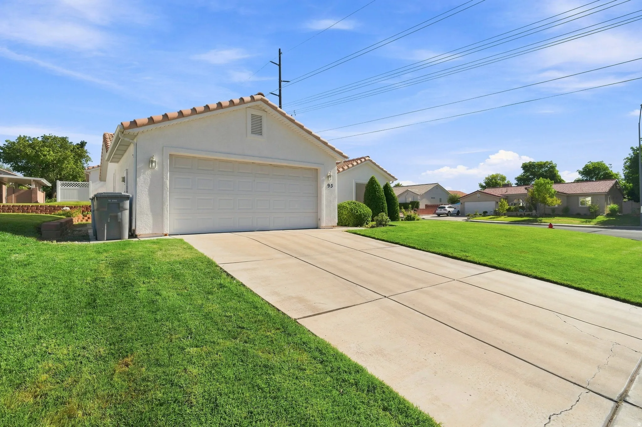 Spacious two-car garage with white paneled overhead door, decorative roof trim, and concrete driveway