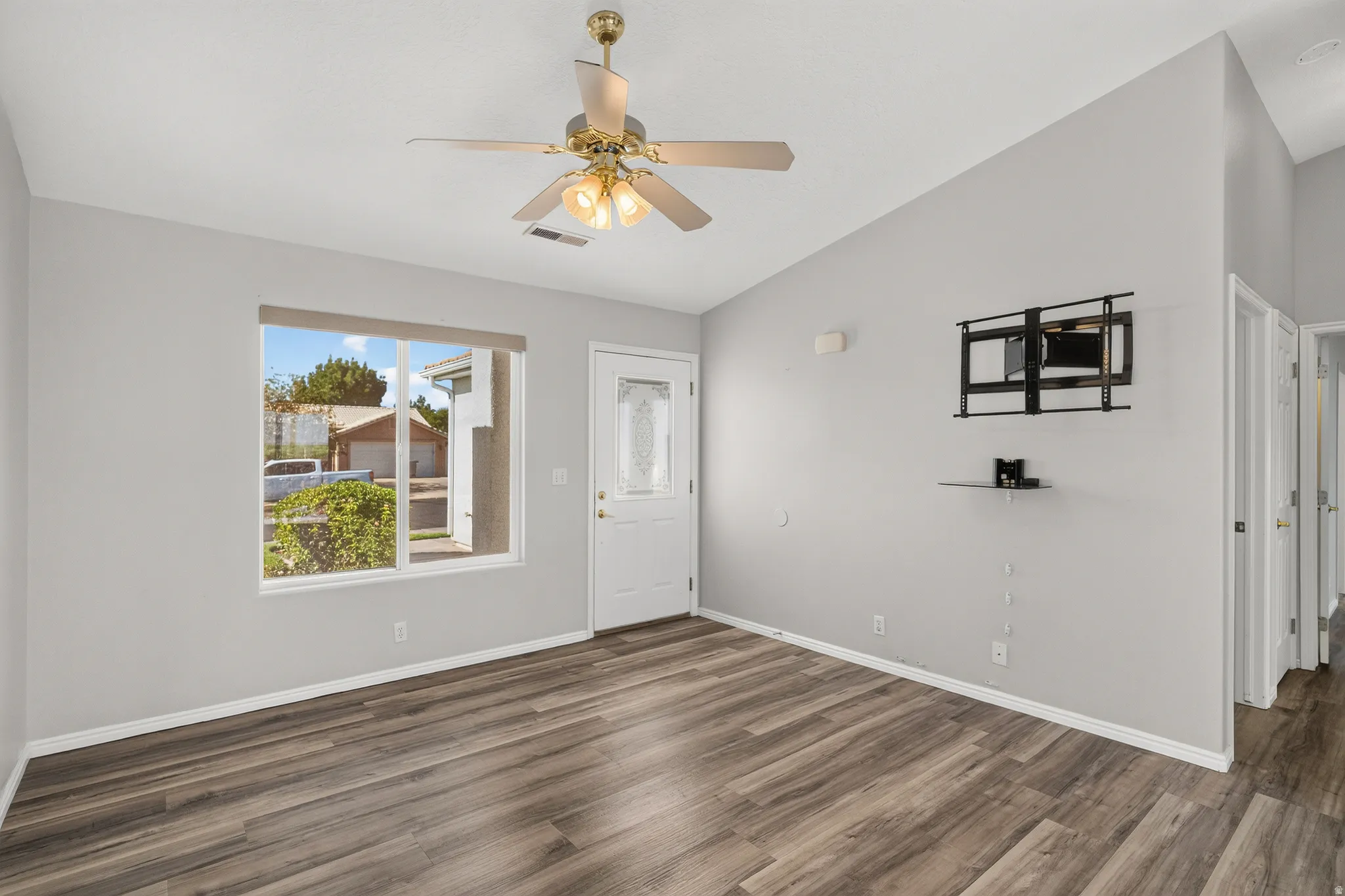 Open concept room featuring wood-finish flooring, a built-in ceiling fan with integrated lighting, and light-toned walls