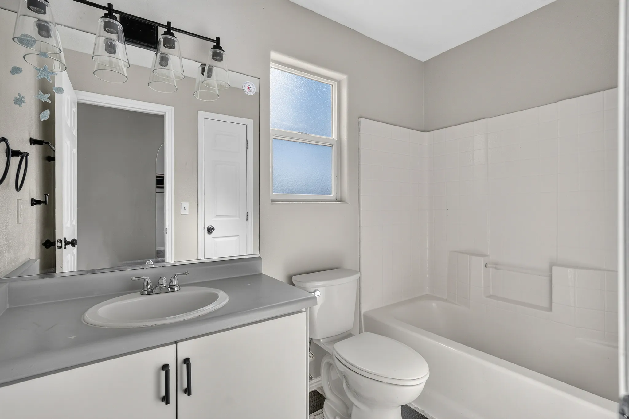 Bathroom featuring a single vanity with an integrated sink, a rectangular mirror, and a white tiled shower/tub combination