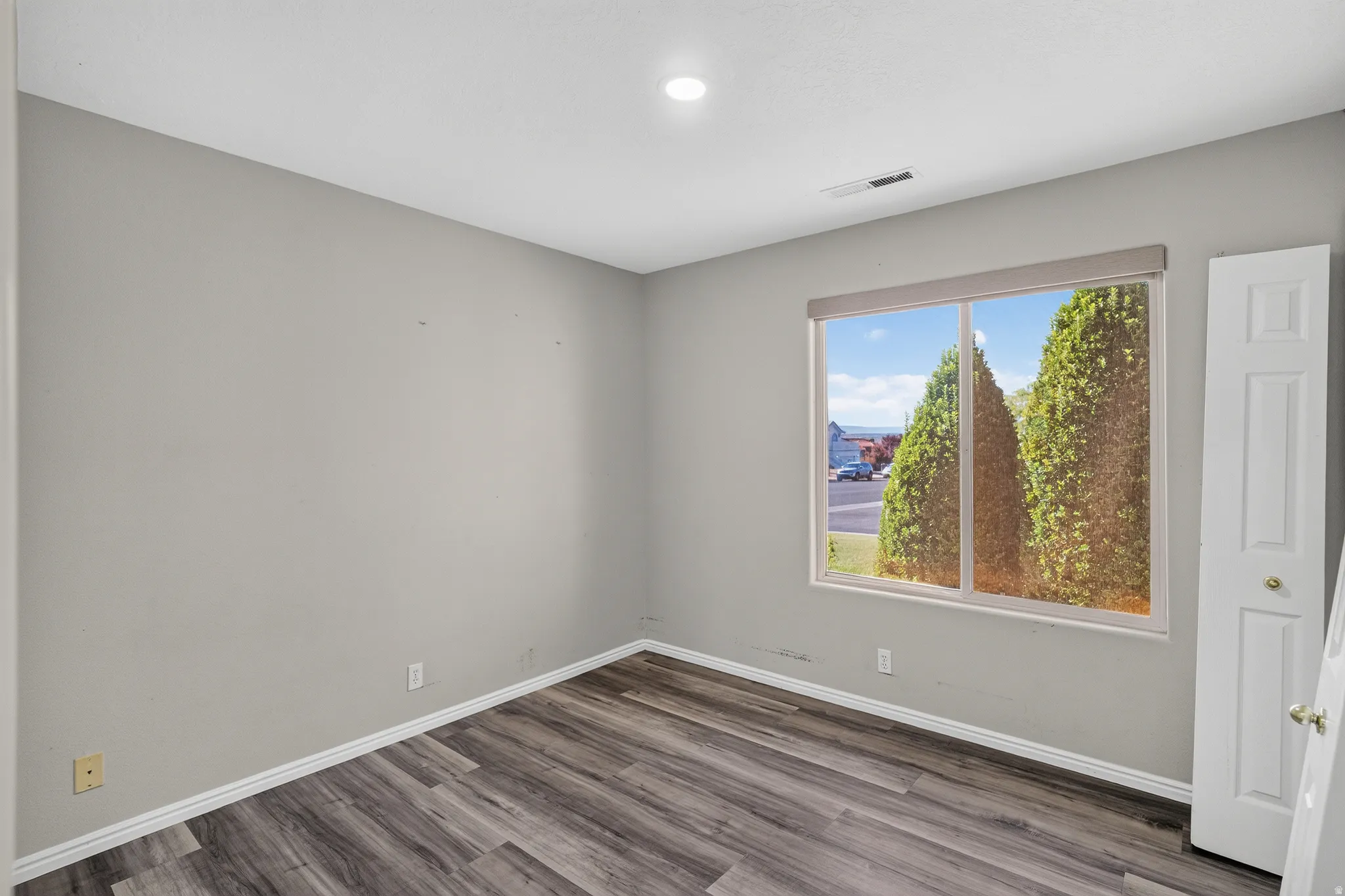 Room featuring wood-finish flooring, light gray walls, and white baseboards