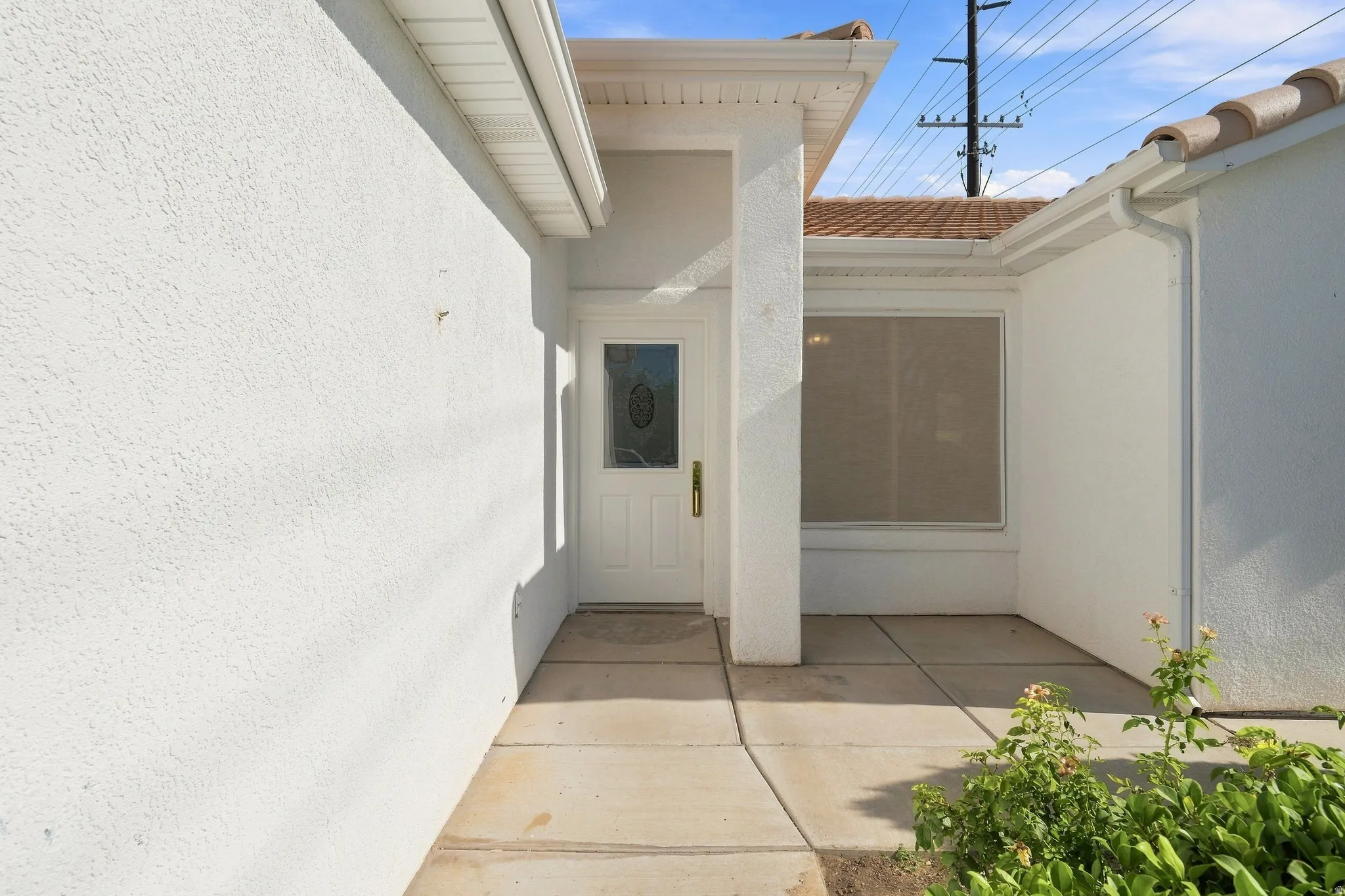Clean, open-air courtyard featuring smooth concrete flooring, white stucco walls, and a covered entry portal