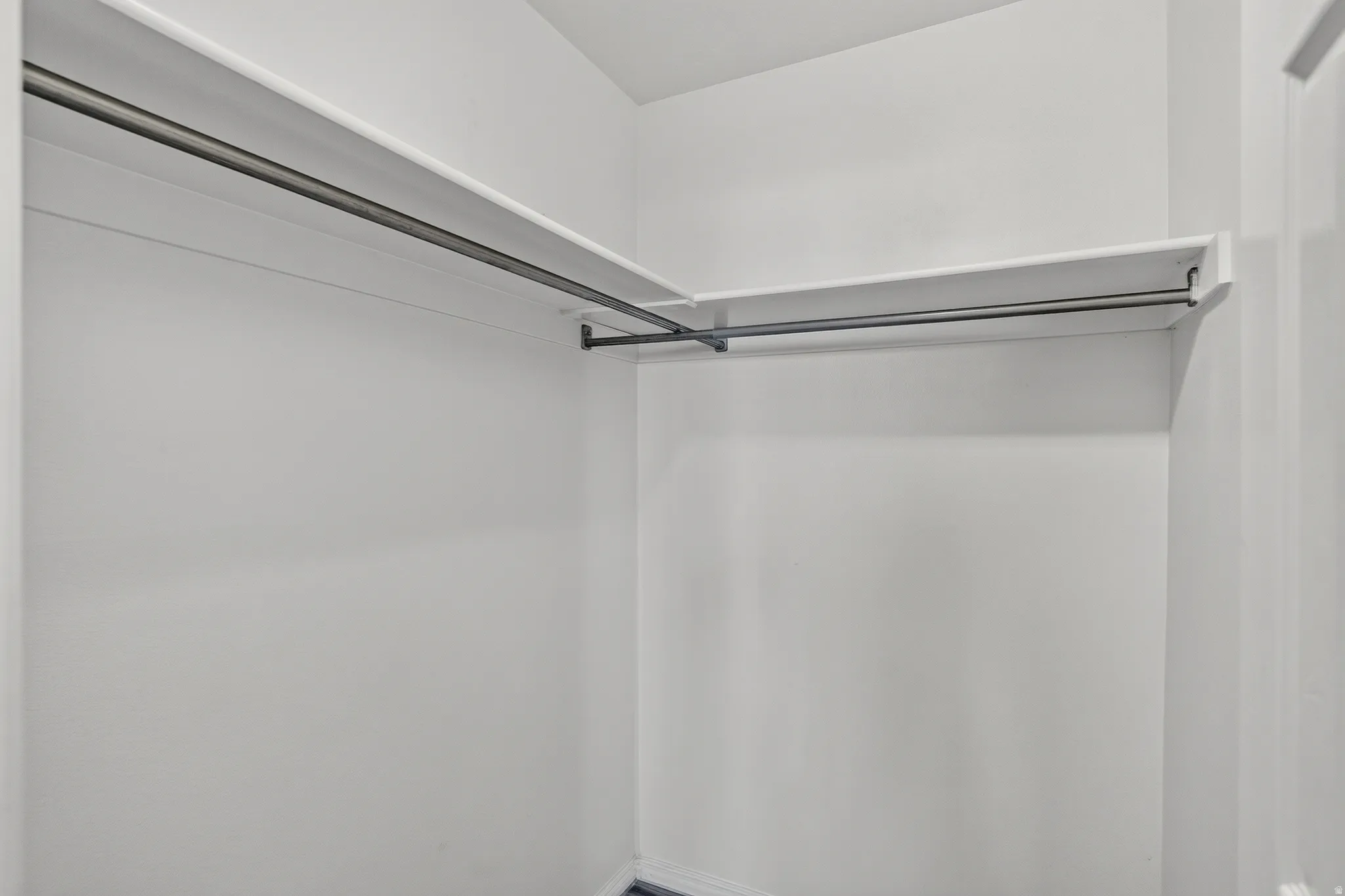 Spacious walk-in closet featuring dual hanging rods with chrome hardware and bright overhead lighting for optimal visibility and storage organization