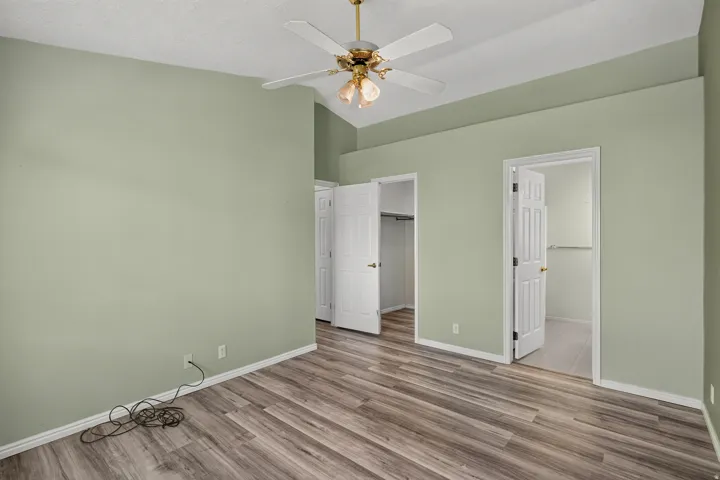 Room featuring wood-finish flooring, vaulted ceiling, and a ceiling fan with integrated lighting