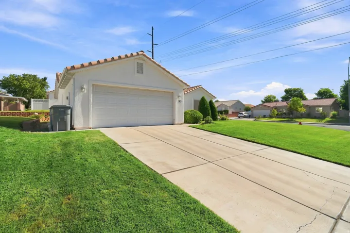 Spacious two-car garage with white paneled overhead door, decorative roof trim, and concrete driveway