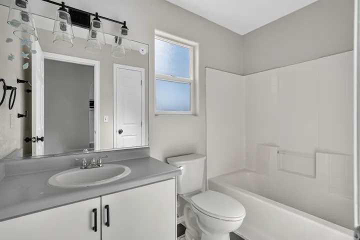 Bathroom featuring a single vanity with an integrated sink, a rectangular mirror, and a white tiled shower/tub combination