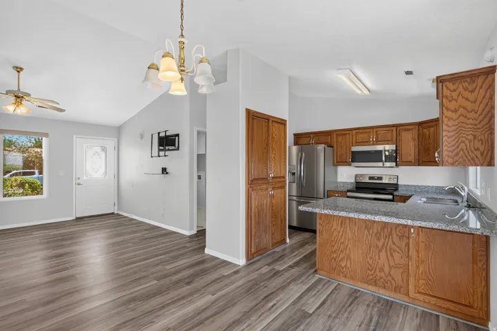Kitchen featuring wood-finish cabinetry, stainless steel appliances, and a granite-style countertop