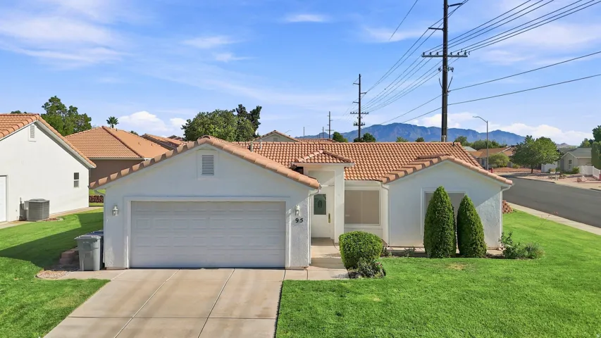 Single-story residence featuring a tile roof, an integrated two-car garage, and a concrete driveway