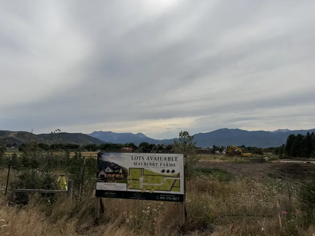 A promotional sign for "Mayberry Farms" featuring a conceptual rendering of a multi-story residence