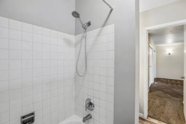 White tiled shower with a chrome showerhead and fixtures