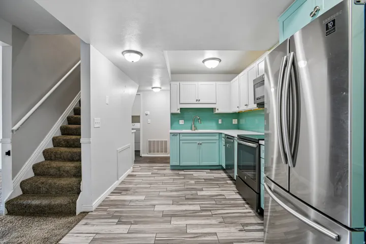 Kitchen featuring stainless steel appliances, two-tone cabinetry, quartz countertops, and a full-height tile backsplash