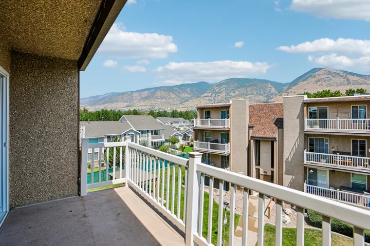Balcony with a white railing, providing expansive mountain scenery and views of nearby buildings