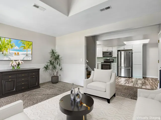 Open-concept living area featuring a cream upholstered armchair, round black accent table, and wood-finish flooring throughout