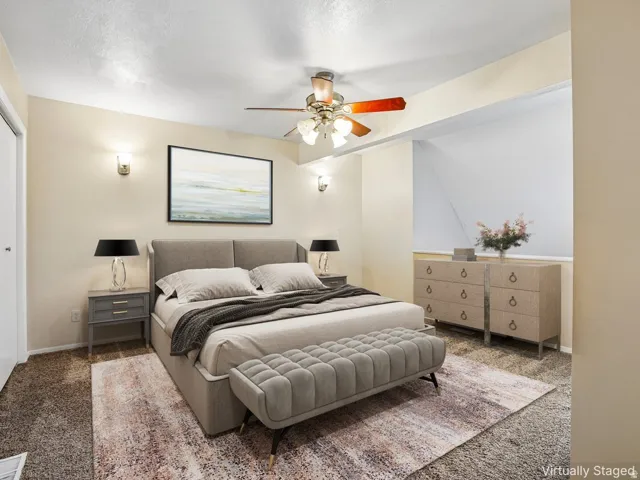 Neutral tone wall paint, wall-mounted sconce lighting, ceiling fan light fixture, sloped ceiling feature, and carpet flooring