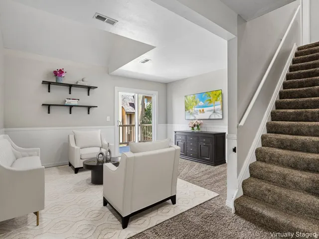 Bright, open foyer featuring neutral wood-finish flooring, white wainscoting, and recessed ceiling lighting