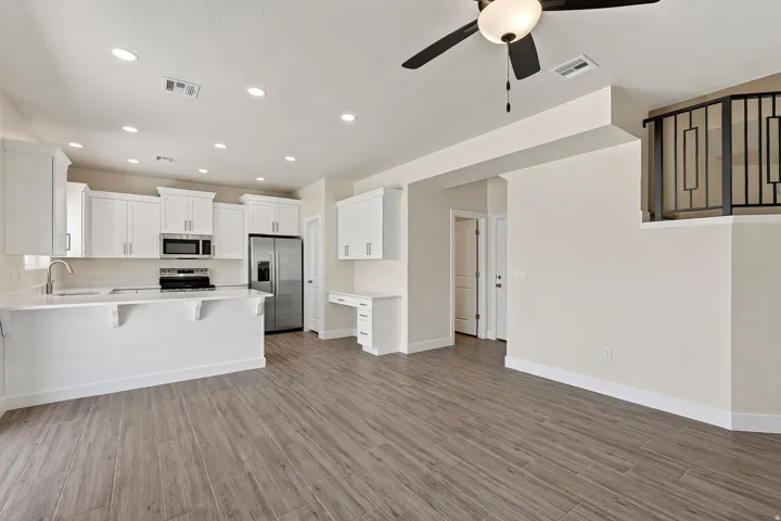 Kitchen with white cabinetry, stainless steel appliances, and wood-finish flooring
