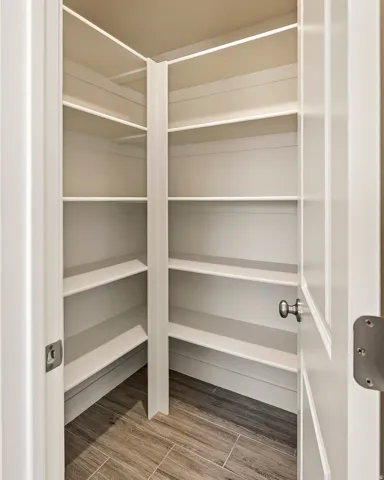 Expansive corner pantry featuring multiple white built-in shelves and wood-look tile flooring