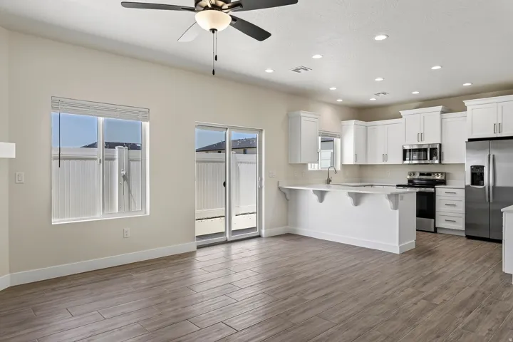 Spacious room featuring wood-finish flooring, a ceiling fan, and recessed lighting