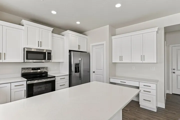 Modern kitchen featuring white shaker cabinetry, stainless steel appliances, a large center island, and wood-finish flooring