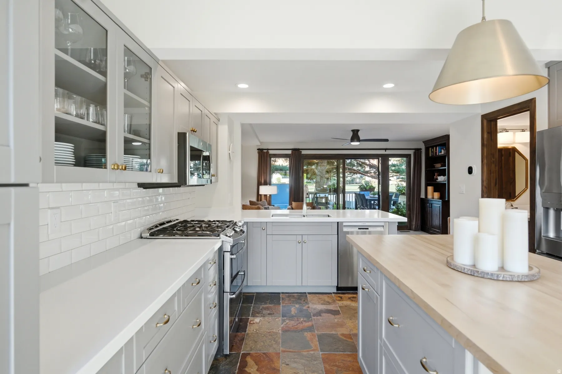 Kitchen featuring light gray cabinetry, white countertops, a white subway tile backsplash, and a multi-tone slate floor