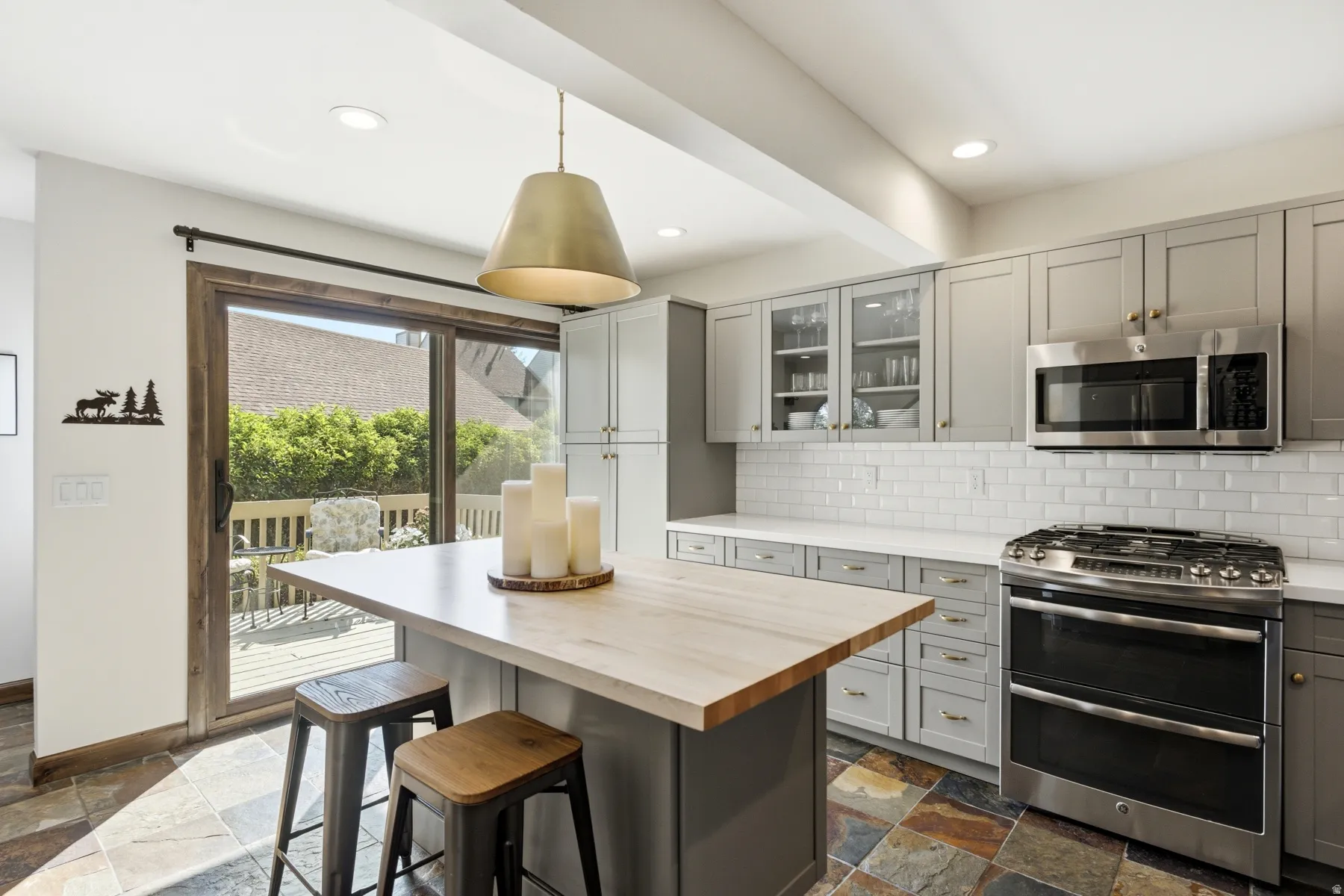 Kitchen featuring a central island with a wood-finish countertop, gray cabinetry, white subway tile backsplash, and stainless steel appliances