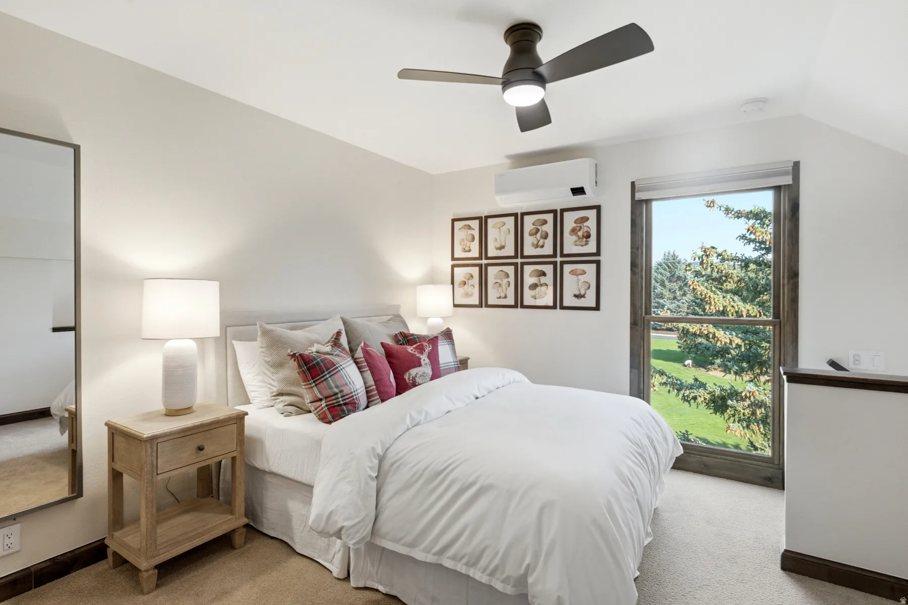 Sloped ceiling, recessed window, dark wood-finish window trim, ceiling fan with integrated lighting, and wall-mounted climate control unit