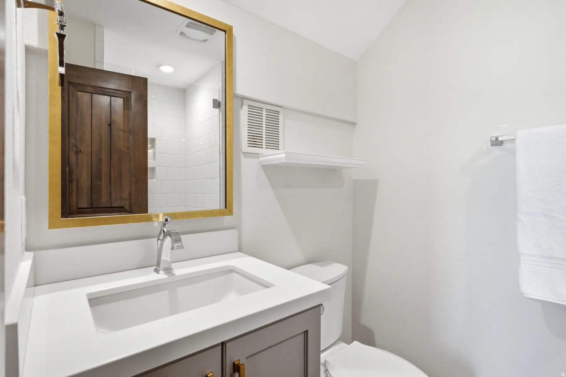 Built-in vanity with a rectangular undermount sink, sleek chrome faucet, and a large framed mirror