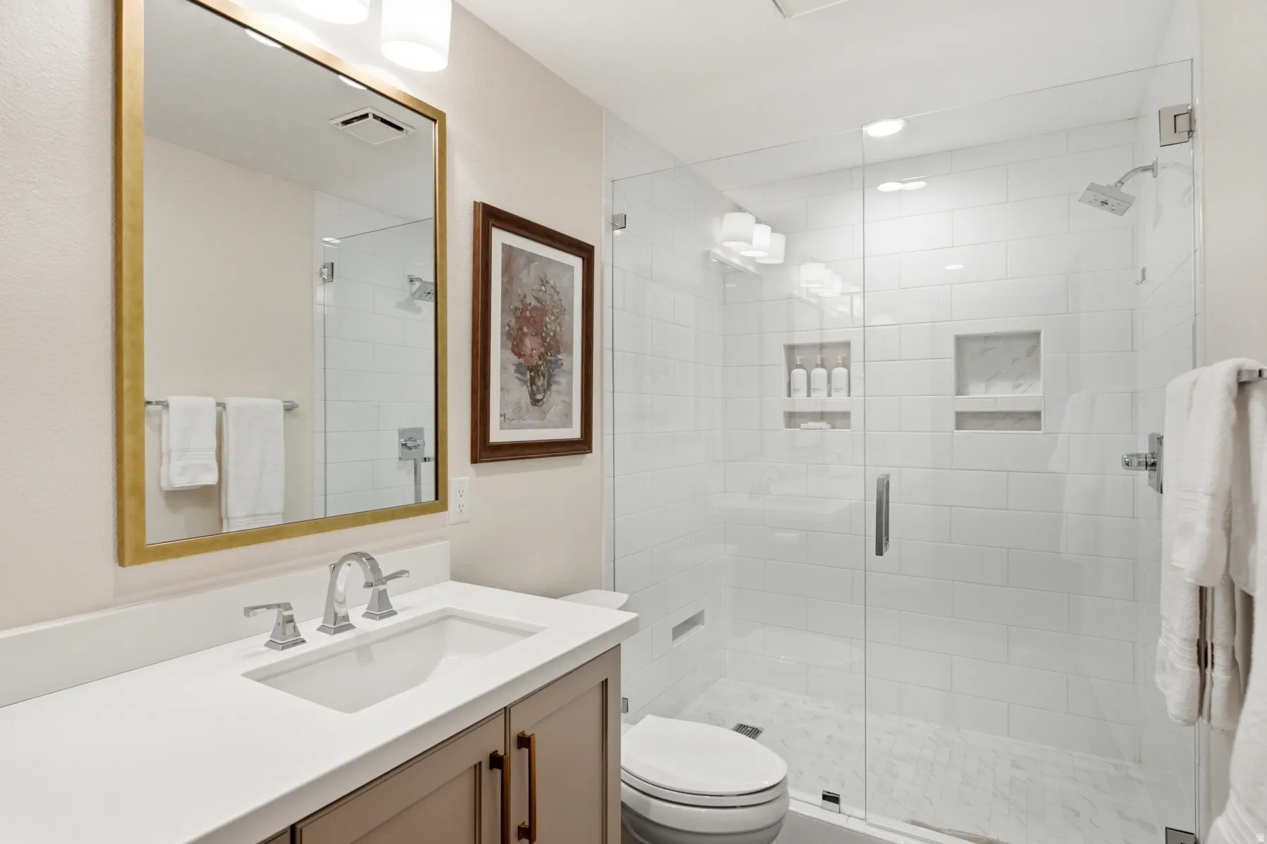 Glass-enclosed shower with subway tile surround and integrated niches