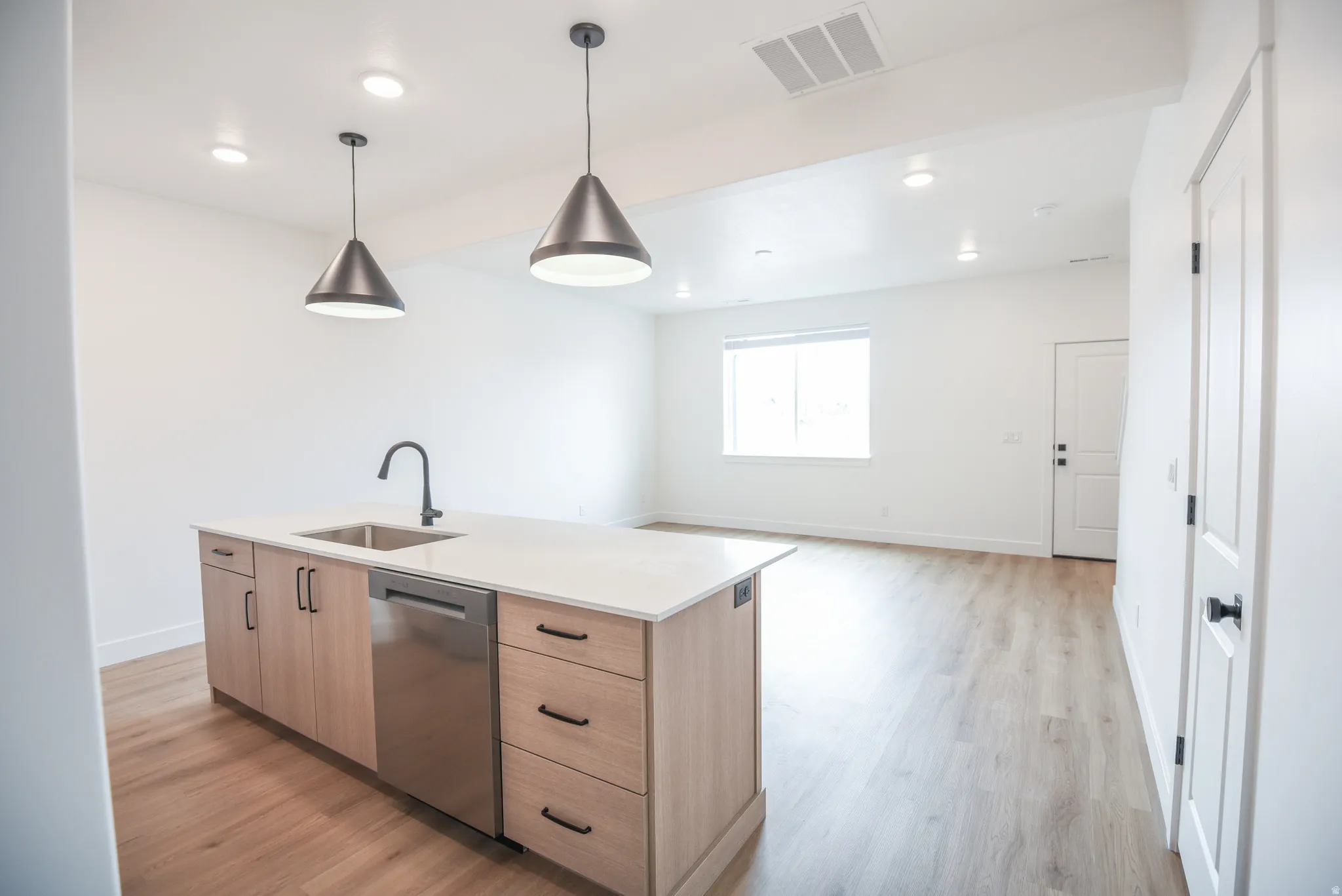 Kitchen island featuring a stainless steel sink, matte black faucet, and wood-finish cabinetry