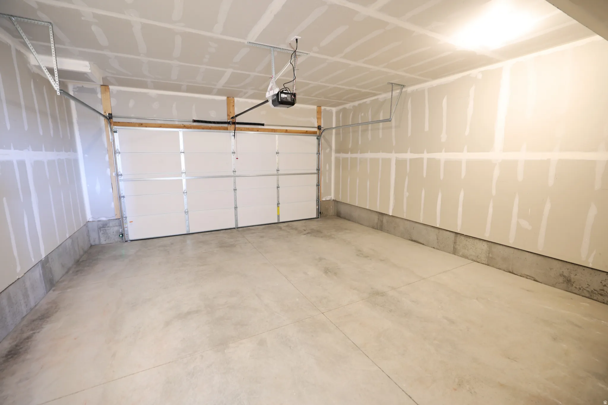 Spacious interior featuring a concrete floor, segmented garage door, and visible garage door opener