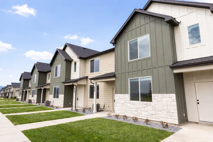 Modern townhome exterior with board and batten siding, stone facade, and dark shingle roofing