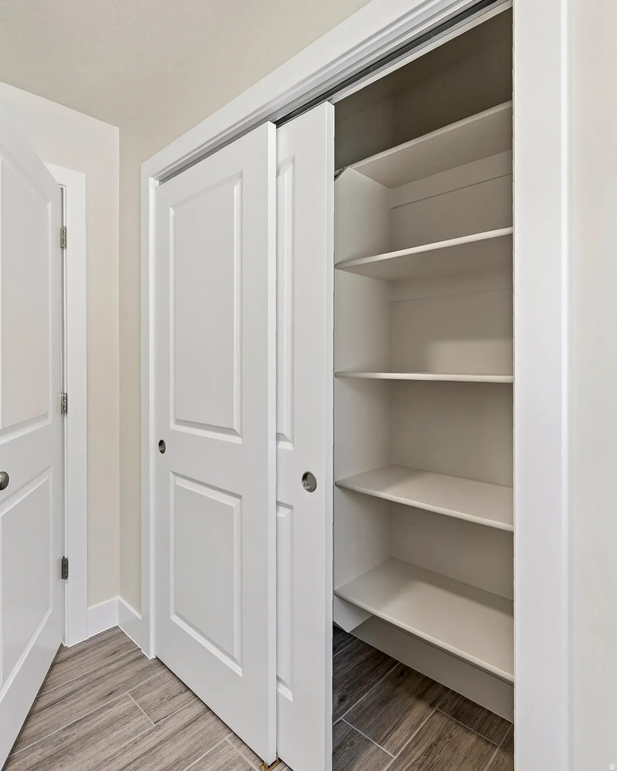 White paneled bi-fold closet doors, integrated shelving, and tile flooring