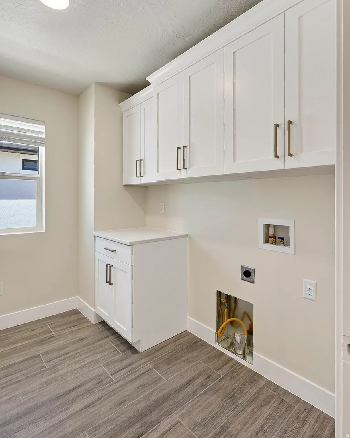 White shaker cabinetry with bronze-finish hardware, built-in countertop, and wood-look tile flooring