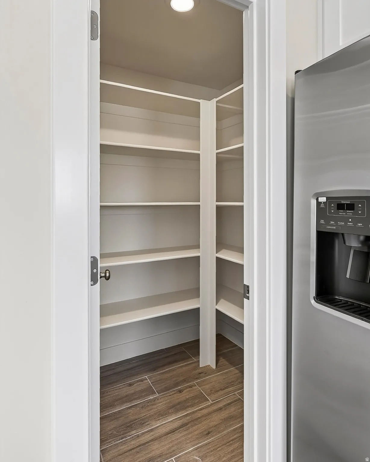 Walk-in pantry featuring extensive shelving, recessed lighting, and wood-finish tile flooring