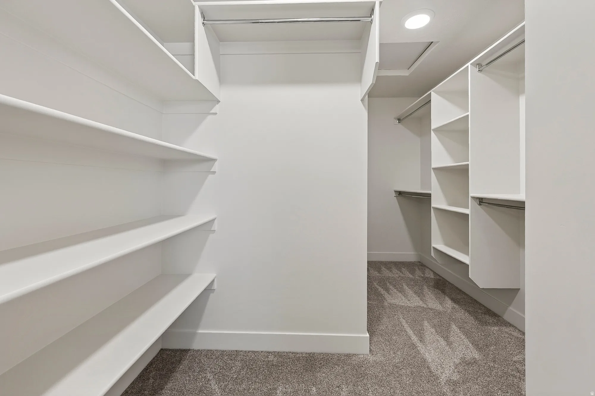 Spacious walk-in closet featuring extensive built-in shelving, hanging rods, and recessed lighting