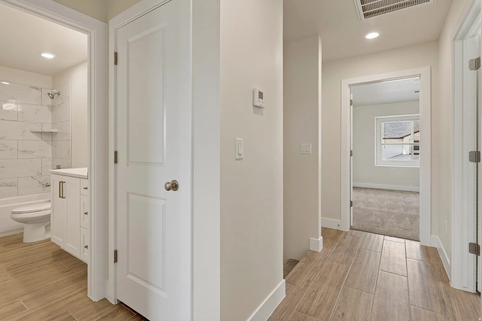 Hallway featuring wood-finish tile flooring, recessed lighting, and white paneled doors